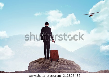 Business man standing on the top of the mountain. Business travel concept