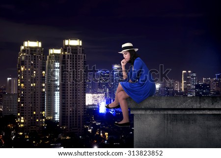 Asian tourist woman sitting on the building rooftop at night time
