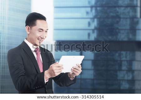 Asian business man working with tablet computer with office building background