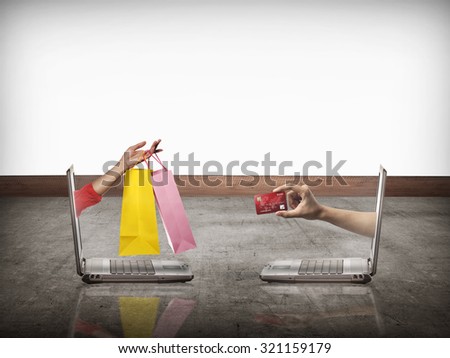 Hand out from computer carry shopping bag, the other show credit card. Online shopping conceptual