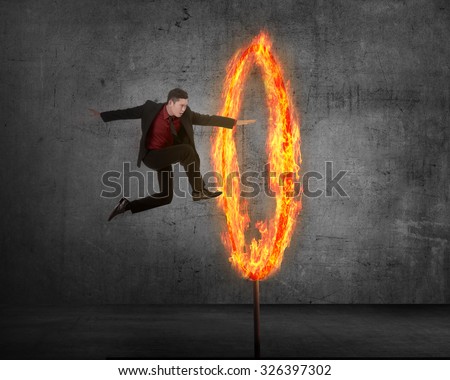 Asian business person jumping through ring of fire. Business risk conceptual