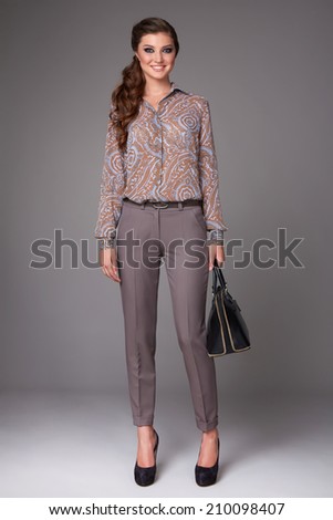Beautiful sexy young business woman with evening make-up dressed in tight pants and silk blouse with lace long sleeves and high-heeled shoes small black handbag business clothes for meetings and walks