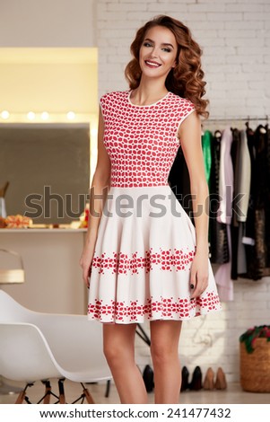Beautiful sexy young girl with blond curly hair and bright evening make-up wearing a short cocktail dress pink photographed in the interior of  clothing store thin body shape diet elegant at the party