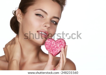 Beautiful sexy brunette woman eating cake shape of heart on a white background, healthy food, tasty, organic, romantic valentines day