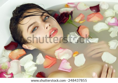 Beautiful young sexy girl with dark hair wet, evening makeup, takes bath with milk tan perfect  skin in romantic atmosphere, beauty cosmetic salon and spa for woman at Valentine\'s Day