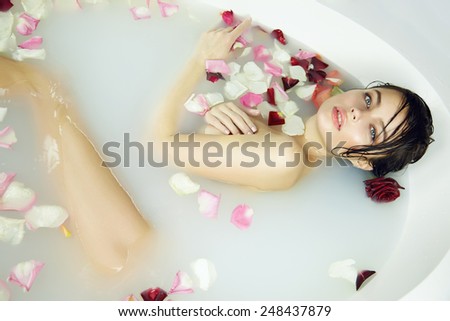 Beautiful young sexy girl with dark hair wet, evening makeup, takes bath with milk tan perfect  skin in romantic atmosphere, beauty cosmetic salon and spa for woman at Valentine\'s Day