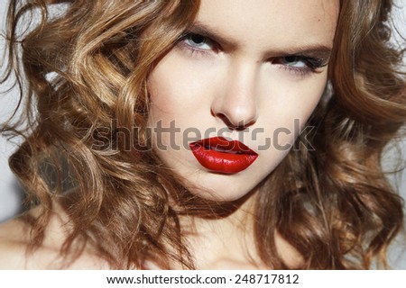 Closeup of the face belong to beautiful young sexy blonde girl with curly hair pure snow white skin and bright makeup red lips, red lipstick, long earrings in emotion