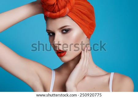 Beautiful young sexy girl with bright makeup perfect slim figure trained body and tan diet fitness club wearing a white stylish trendy top and orange headscarf sport underwear