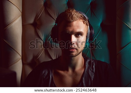 Young stylish trendy guy sitting musician DJ headphones for musical instruments and laptop with speakers