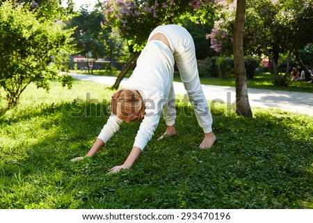 Beautiful young woman sexy blonde girl with make-up walks in the park, doing exercises, sports, yoga or gymnastics dressed in light tracksuit or pleasure spring summer nature sunny warm morning smile