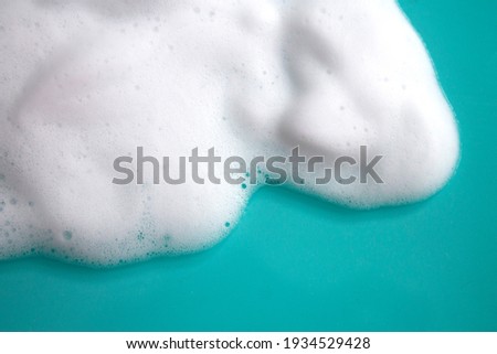 Foam soap or shampoo. Foaming liquid on a blue background. White foam shampoo. A sample of a cosmetic product is mousse, shampoo, or soap. Skin care, cosmetology and beauty concept.