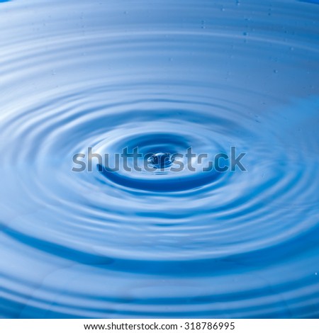 a water drop impact with water surface, causing rings on the surface.