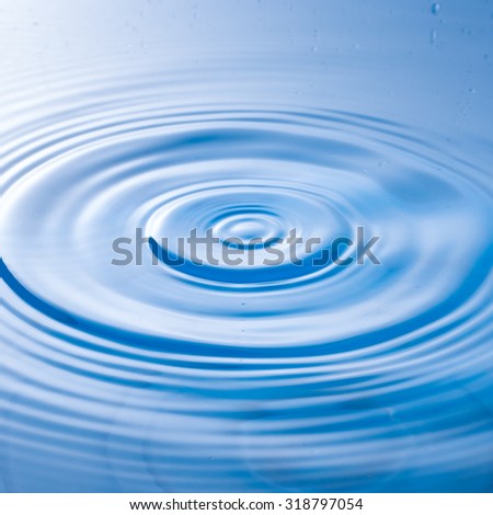 a water drop impact with water surface, causing rings on the surface.