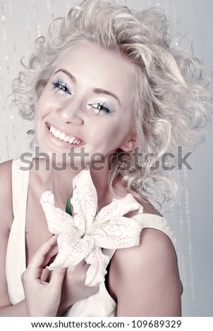 Beautiful smiling young female with original make up, hairdress and flower