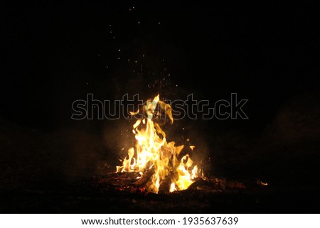 Night campfire in the winter forest. Sparks from the fire