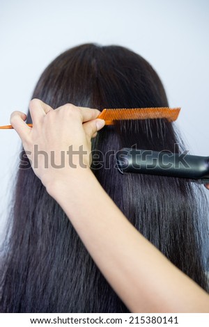 Combing healthy long straight female hair - close-up,Cropped image of hairstylist\'s hand combing client\'s hair in parlor
