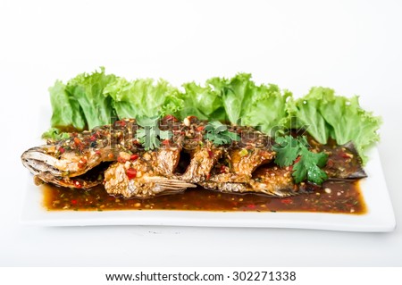 Crispy fry grouper is topped with chili sauce on white dish,fried grouper fish with sauce,