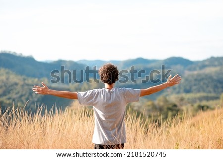 Man with open arms in the middle of the grass contemplating nature or expressing gratitude. Concept of happiness, mental health and well being. Foto stock © 