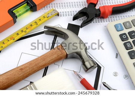 measuring tape, hammer, pliers, gloves and water level on plans