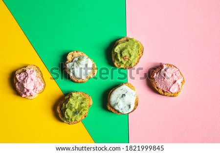 Appetizing crostini or bruschetta with tarama, tzatziki and guacamole sause. Variety of small sandwiches with various toppings on the multicolored background Stok fotoğraf © 