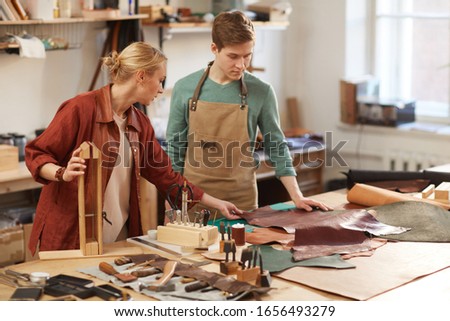 Young Caucasian man and woman working together on new handicraft in leather craft workshop, copy space Сток-фото © 