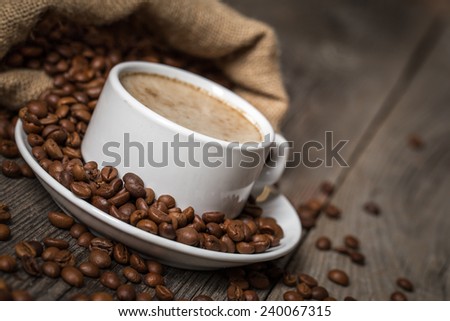 White coffee cup with coffee bag made from burlap sack on wooden table