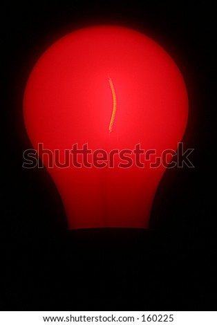 Red light bulb showing glowing filament inside. Vertical on black background.