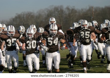 High school football players charging on to the field. Editorial use.