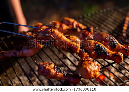 chicken drumsticks are grilled on a barbecue grill in the evening. cooking chicken meat on open flame bbq grill