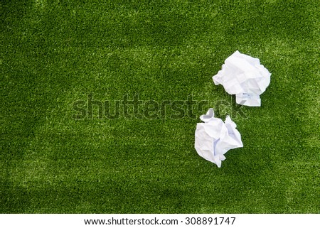 Two crumpled paper ball on green grass