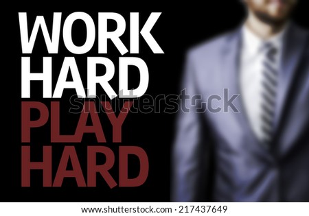 Work Hard Play Hard written on a board with a business man on background