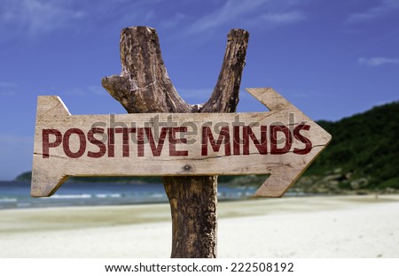 Positive Minds wooden sign with a beach on background