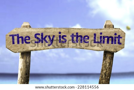 The Sky is The Limit wooden sign with a beach on background