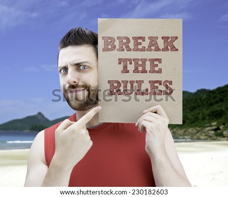 Man holding a card with the text Break The Rules on a beach background