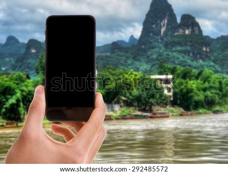 Hand holding mobile smart phone with black screen on exotic background