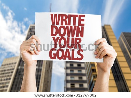 Write Down Your Goals placard with cityscape background