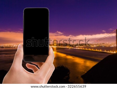 Hand holding mobile with black screen on Golden Gate Bridge background