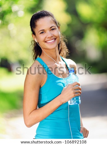 Portrait of a runner listening to music on headphones and holding water bottle. healthy wellness fitness lifestyle.