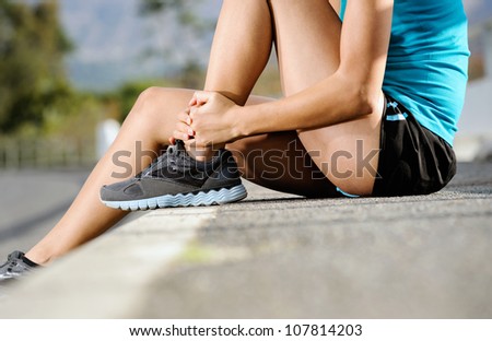 runner with ankle injury holds foot to reduce pain. running problem for athlete training outdoors