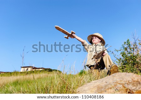 young child playing pretend adventure explorer with wooden sword and treasure map.