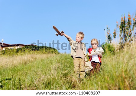 Brother and sister children playing pretend adventure game outdoors having fun in the field