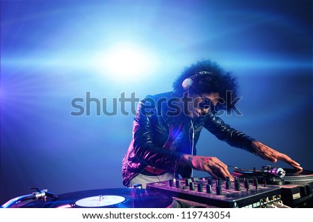 nightclub dj playing music on deck with vinyl record headphones light flare clubbing party scene