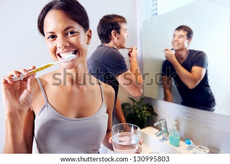 Bathroom routine for happy young couple brushing teeth and shaving in mirror