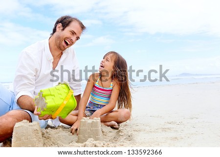 happy healthy family father and daughter building sand castle on the beach smiling and carefree