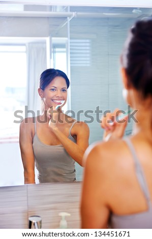 Portrait of attractive woman brushing teeth in bathroom and looking in the mirror at reflection. healthy teeth.