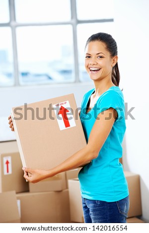 portrait of adorable girl moving into new home holding box