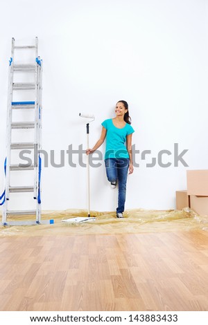 woman deciding what color to paint the wall of new apartment holding painting roller