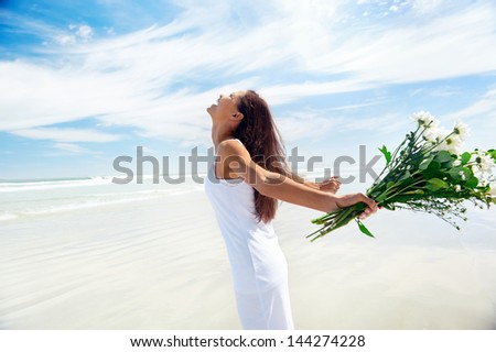 woman with arms out freedom girl on beach with flowers in summer