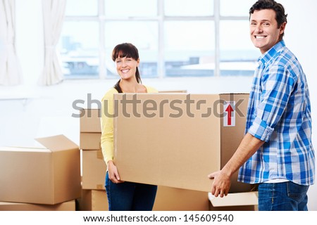 Happy couple carrying boxes moving into new home apartment house