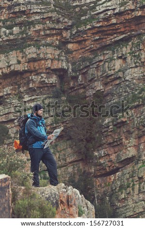 Man with map exploring wilderness on trekking adventure